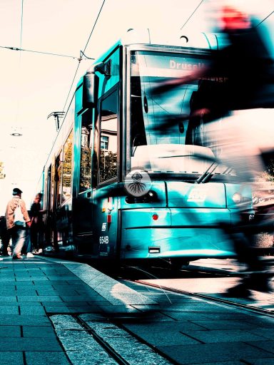 Street One II 2023 WEB Menschen steigen in eine Straßenbahn während Fragmente eines Fahrrads vorbei fahren