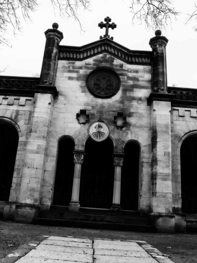 Cemetary Sessions I 2022 WEB Das Portal zu einer Gruft in schwarzweiß. Es wirkt sehr düster, weil es auch leicht gedreht ist.